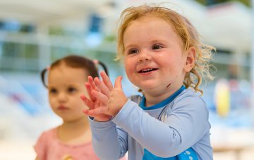 Toddler clapping under outdoor shaded area
